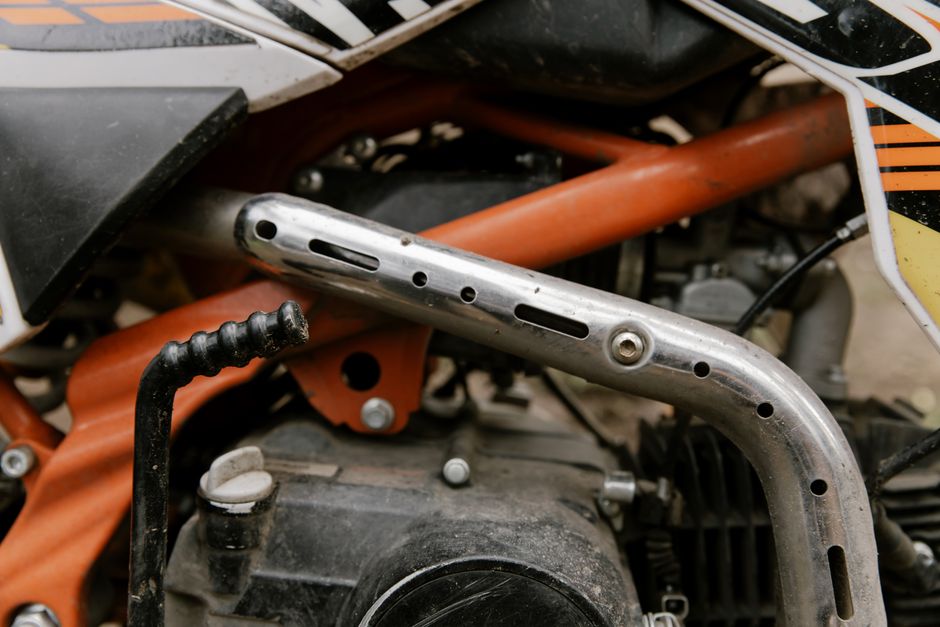 Detailed close-up of a dirt bike's exhaust and engine, showcasing metallic components and design.