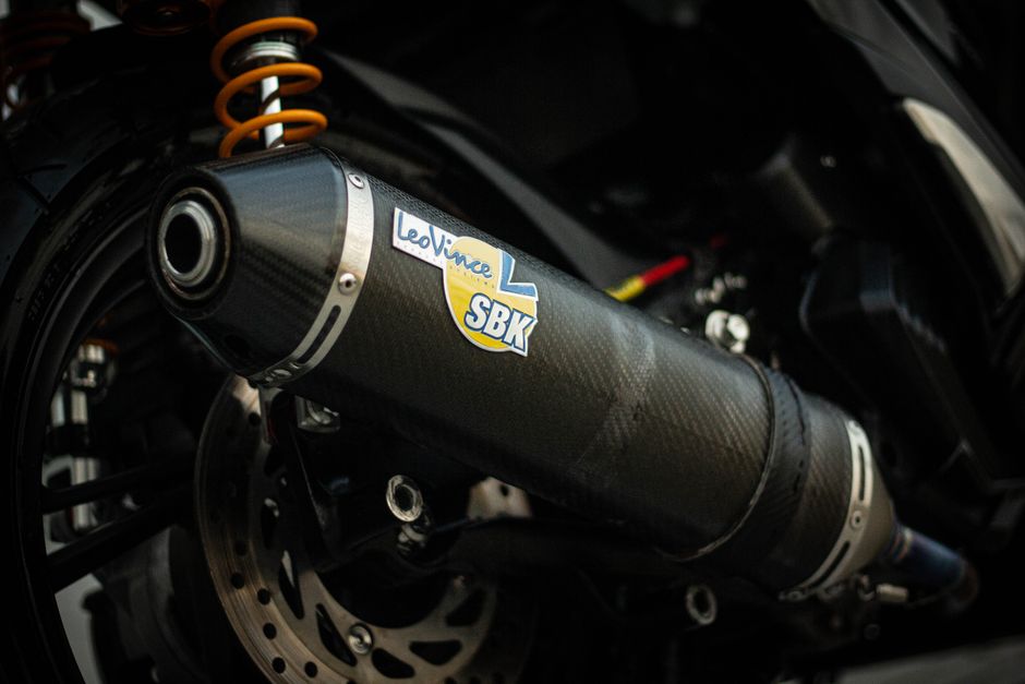 Detailed view of a carbon fiber motorcycle exhaust with LeoVince branding. Perfect for automotive enthusiasts.